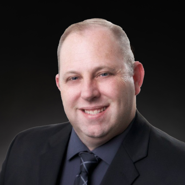 A man in a dark suit and tie poses for a professional headshot against a dark background.